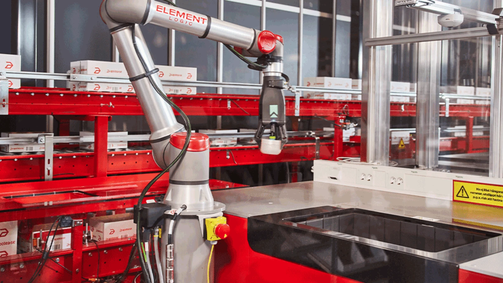 Element Logic Roboterarm greift Pakete in einem automatisierten Lager mit roten Regalen.